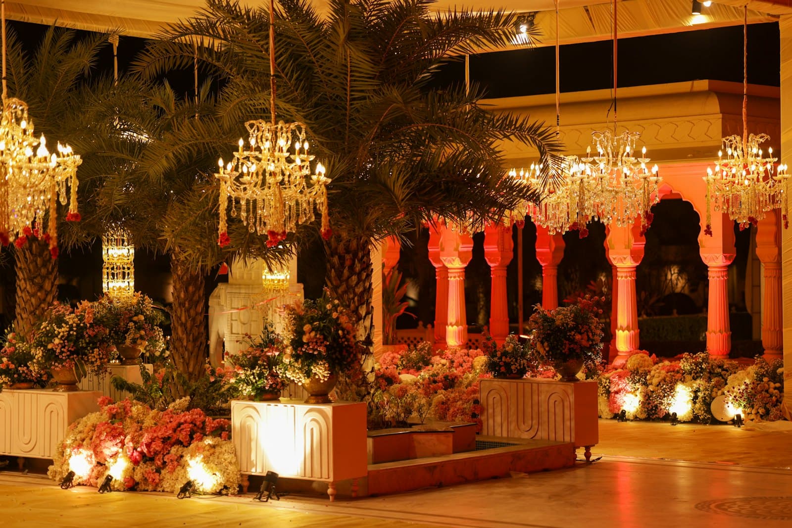 A wedding venue interior with chandeliers and large floral arrangements.